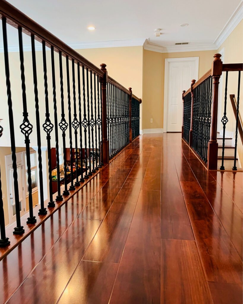 Long hardwood hallway beside decorative iron balusters
