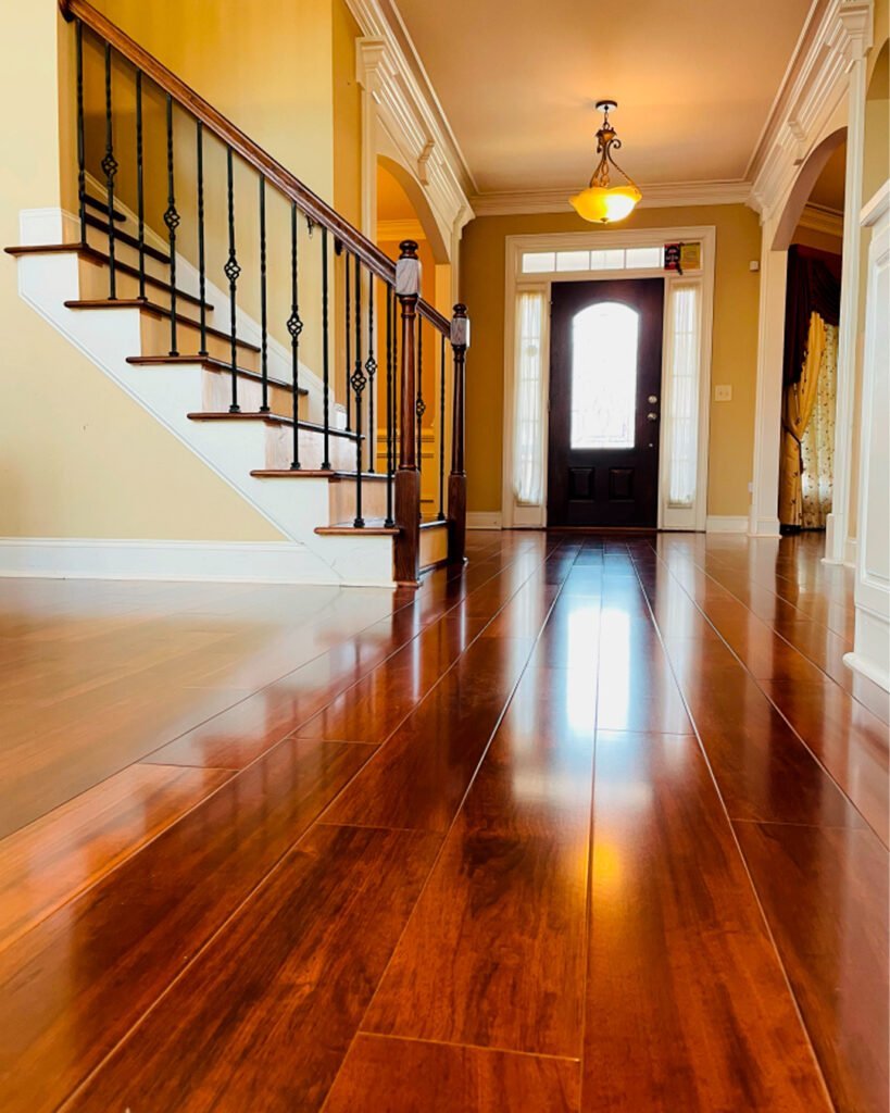 Glossy hardwood floor running through a front foyer toward the entry door