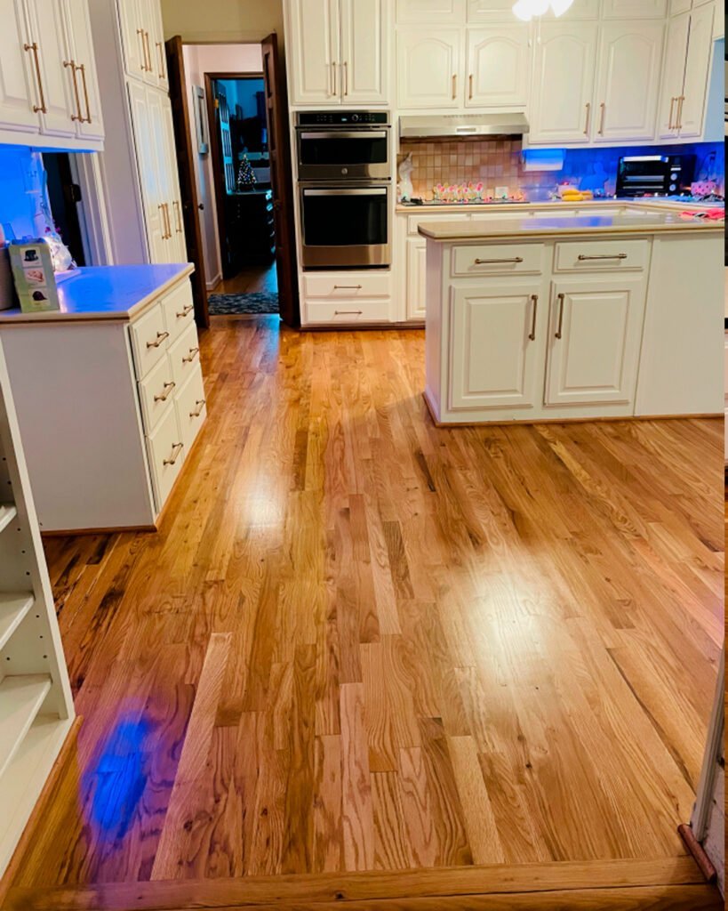 Oak hardwood floor running into a white kitchen