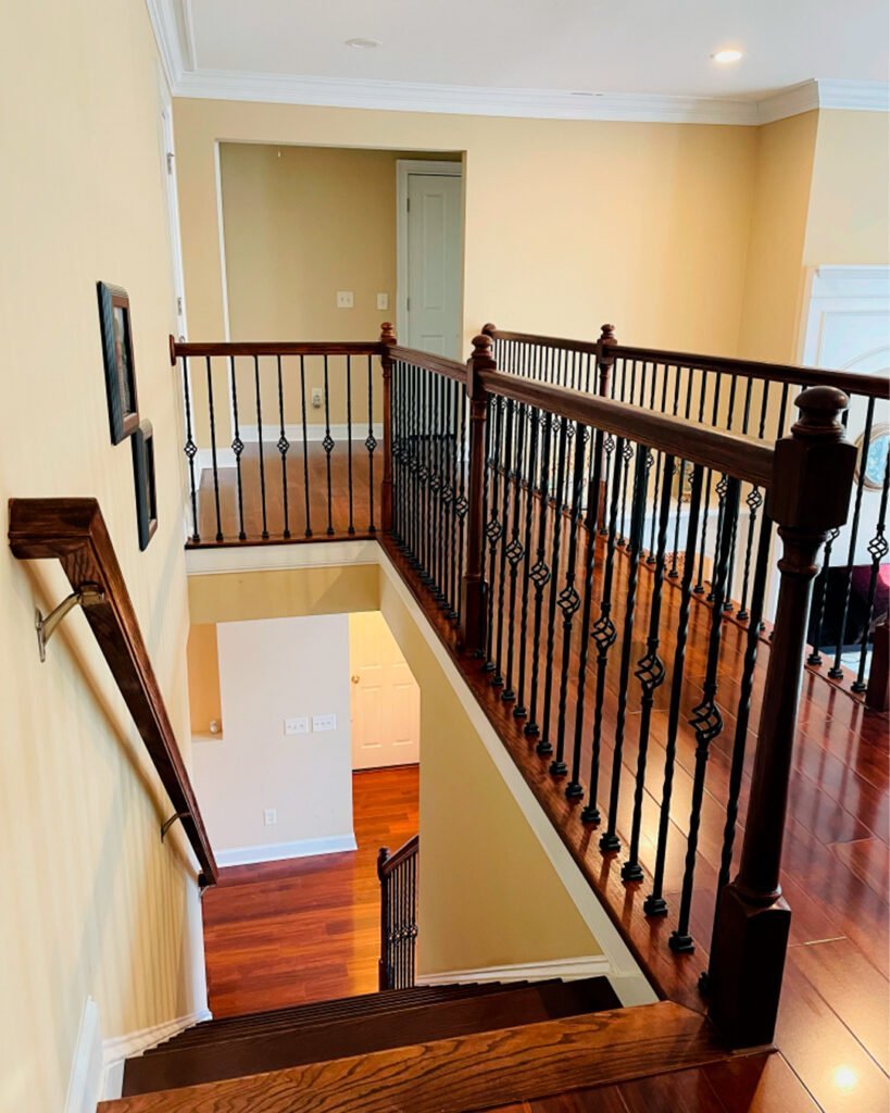Upper landing with iron balusters and a stained handrail