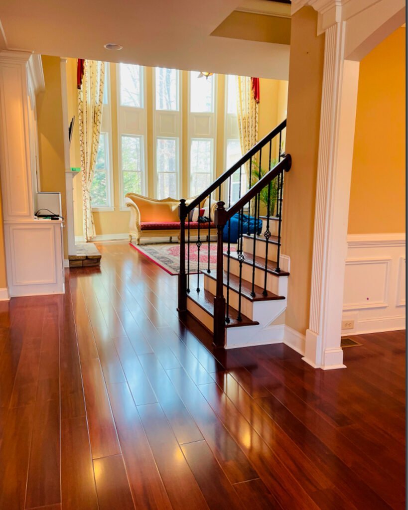 Hardwood living room floor beside a staircase with a tall window